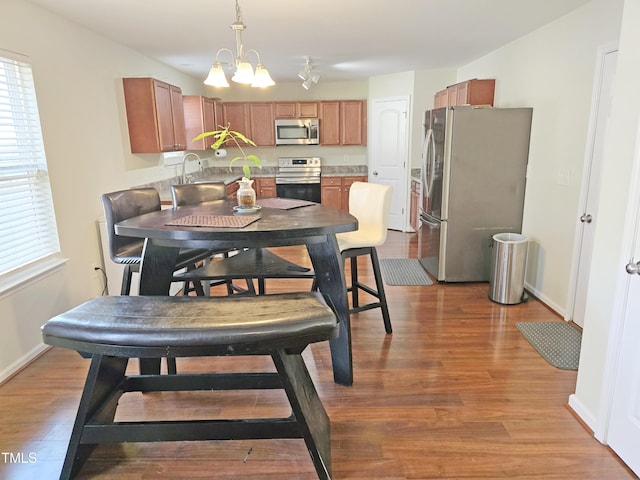 dining room with light wood-style flooring, baseboards, and an inviting chandelier