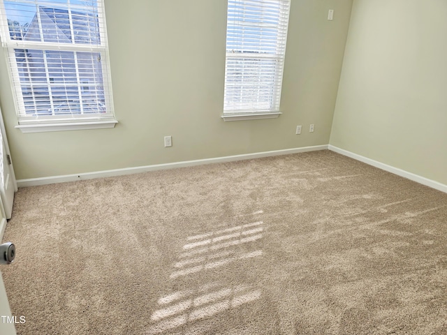 carpeted empty room featuring baseboards