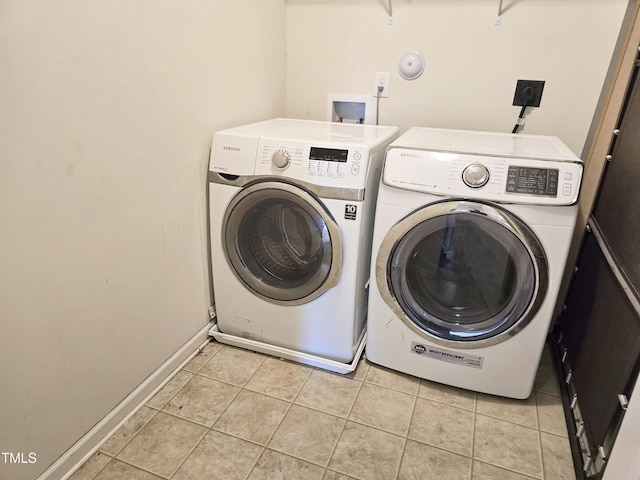 washroom with laundry area, light tile patterned flooring, baseboards, and washing machine and clothes dryer