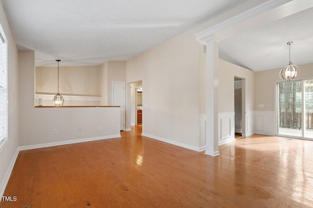 interior space with wood-type flooring, a wealth of natural light, a textured ceiling, and ornate columns