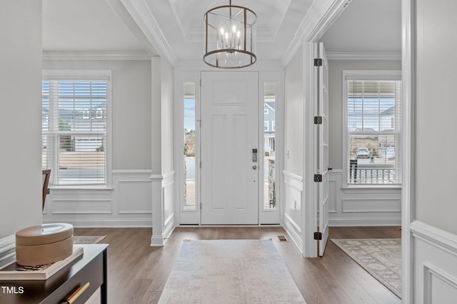 entryway with ornamental molding, plenty of natural light, and light wood-type flooring