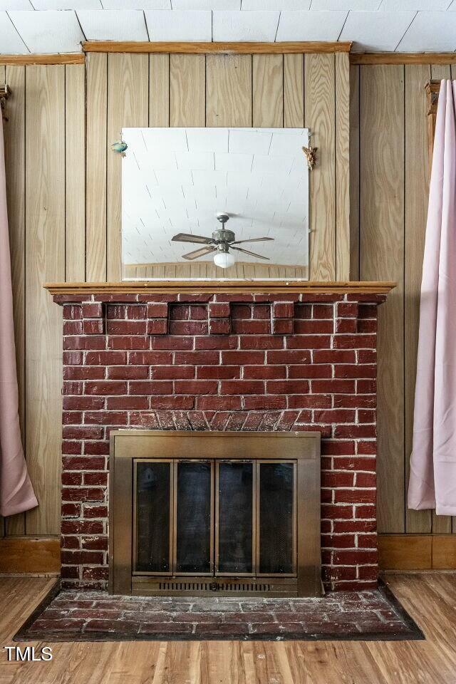 interior details with ceiling fan, wood-type flooring, and a fireplace