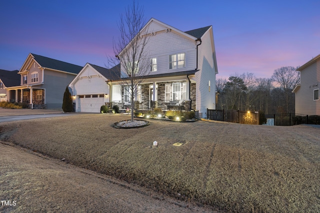 view of property featuring a garage, a lawn, and covered porch