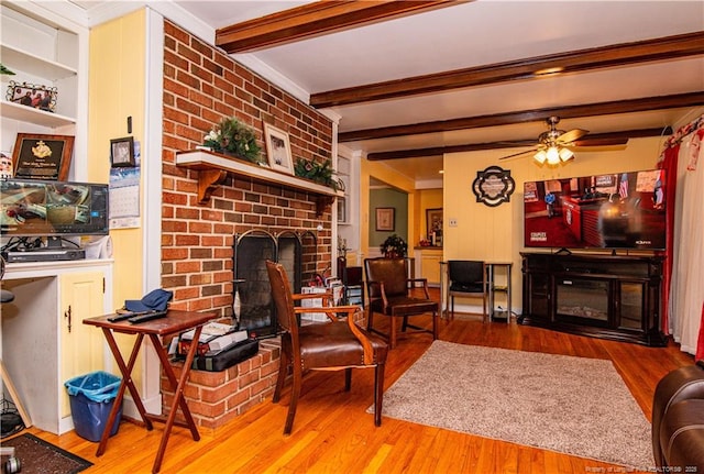 living room with beam ceiling, a fireplace, ceiling fan, and light wood-type flooring