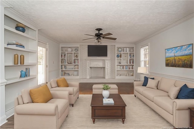 living room with built in features, a healthy amount of sunlight, wood-type flooring, and a textured ceiling