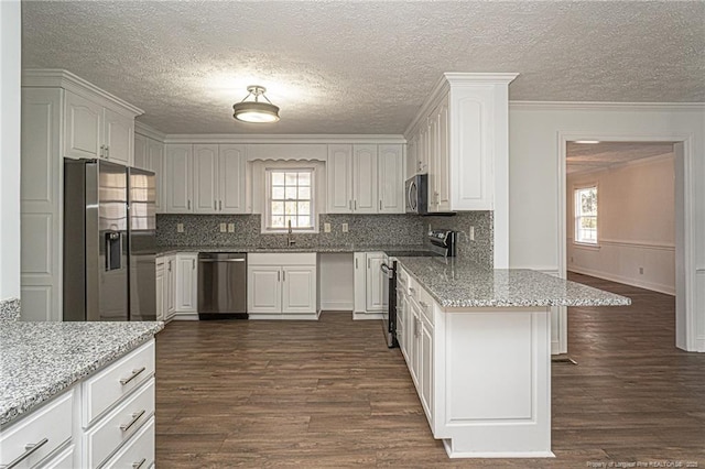 kitchen with light stone counters, white cabinetry, and stainless steel appliances