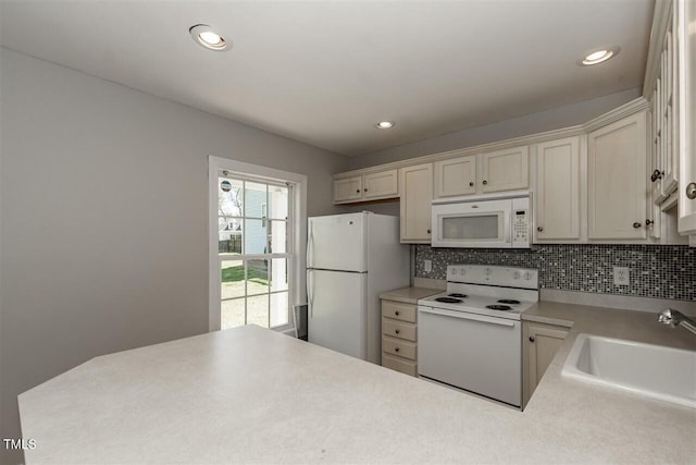 kitchen with sink, white appliances, and decorative backsplash