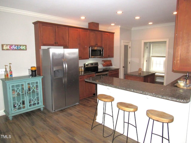 kitchen with crown molding, a kitchen island, a breakfast bar, and appliances with stainless steel finishes