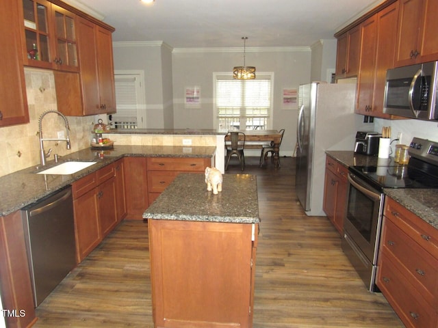 kitchen featuring sink, decorative light fixtures, ornamental molding, a kitchen island, and stainless steel appliances