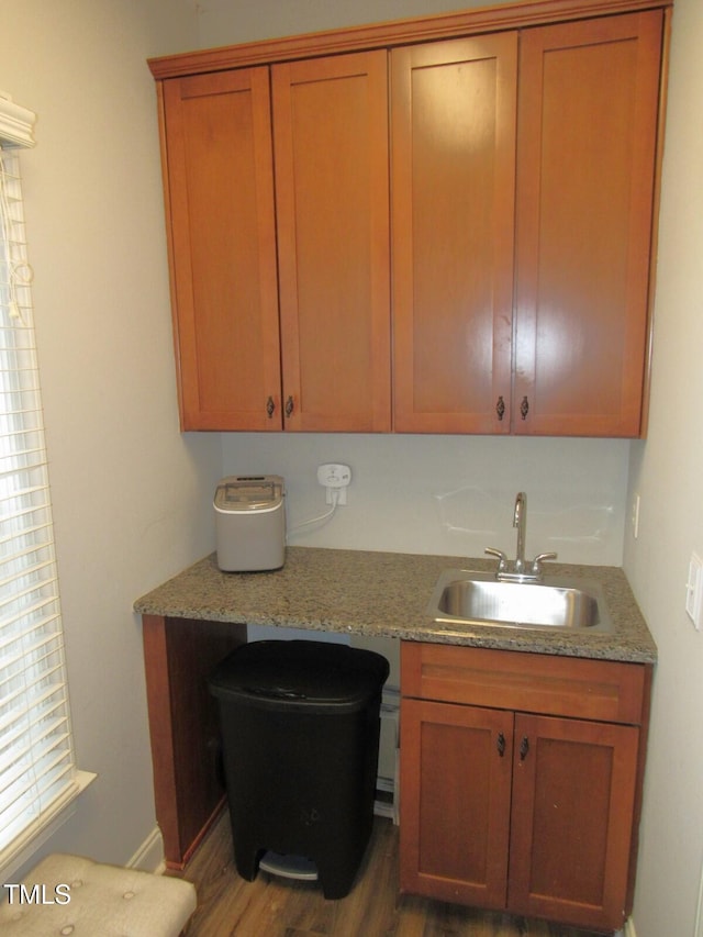 kitchen featuring light stone counters, sink, and hardwood / wood-style floors