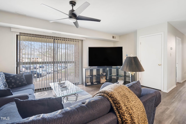 living area with visible vents, baseboards, wood finished floors, and a ceiling fan