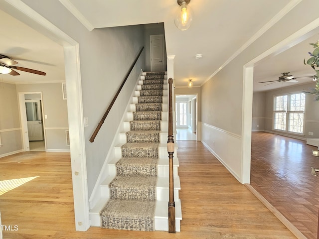 stairs featuring hardwood / wood-style flooring, ornamental molding, and ceiling fan