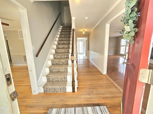 staircase with hardwood / wood-style floors, crown molding, and ceiling fan