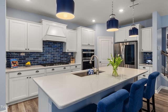 kitchen with white cabinetry, appliances with stainless steel finishes, and an island with sink