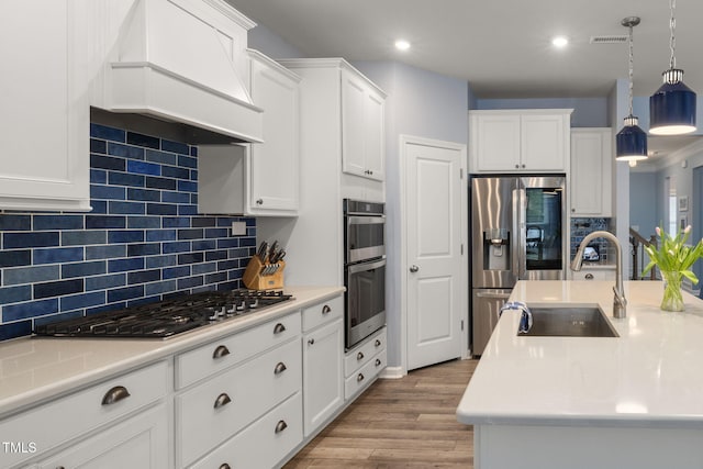 kitchen featuring sink, premium range hood, backsplash, stainless steel appliances, and decorative light fixtures