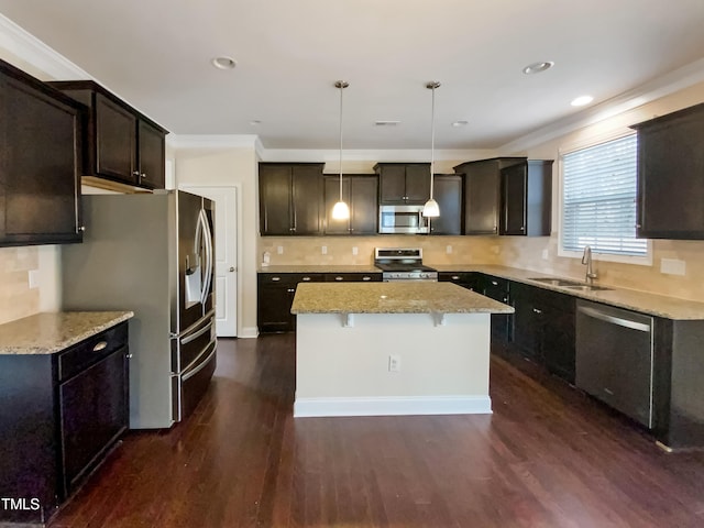 kitchen with sink, dark wood-type flooring, stainless steel appliances, a kitchen island, and decorative light fixtures