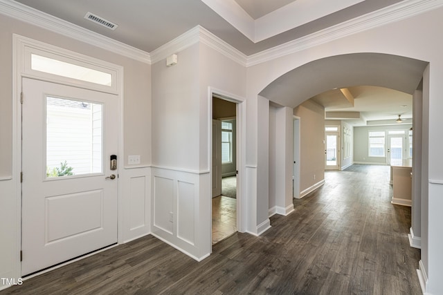 foyer featuring arched walkways, wainscoting, ornamental molding, visible vents, and dark wood-type flooring