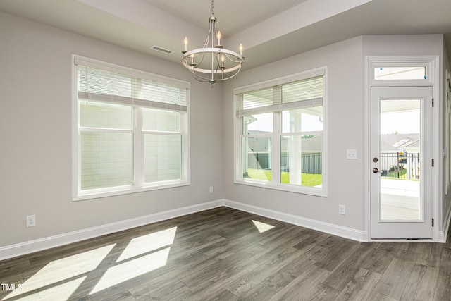 unfurnished dining area with dark wood-style floors, an inviting chandelier, visible vents, and baseboards