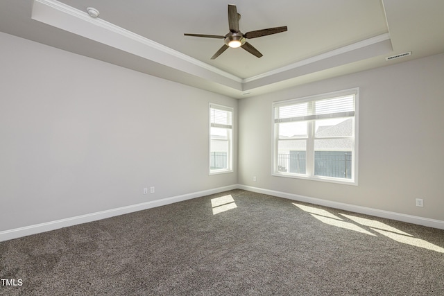 carpeted spare room with crown molding, visible vents, a tray ceiling, baseboards, and a ceiling fan