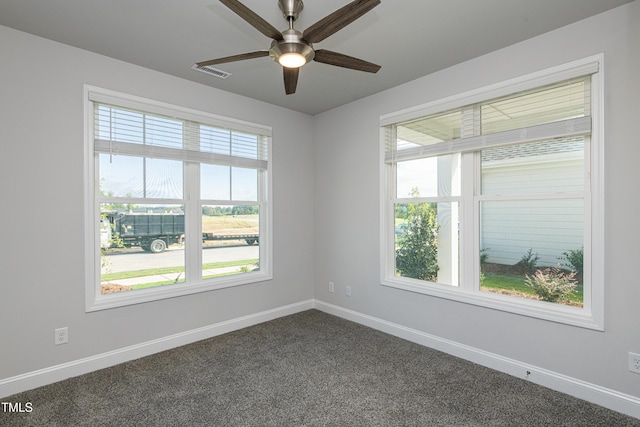 unfurnished room featuring dark carpet, visible vents, ceiling fan, and baseboards