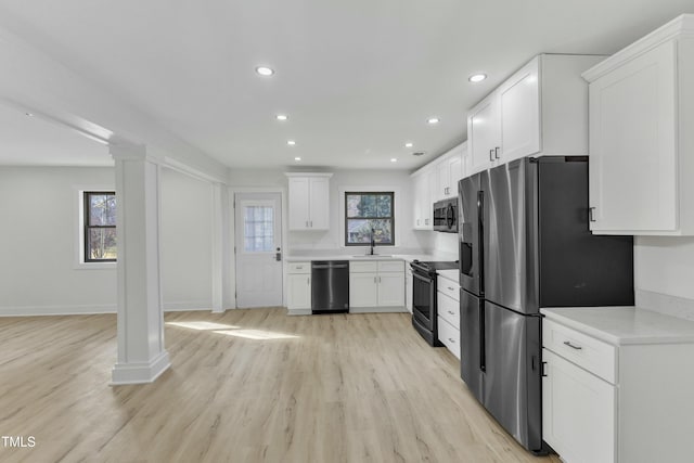 kitchen featuring plenty of natural light, stainless steel appliances, light wood-type flooring, and white cabinets