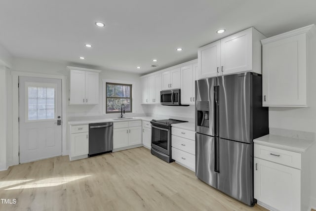 kitchen with white cabinetry, sink, light hardwood / wood-style flooring, and appliances with stainless steel finishes