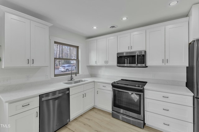 kitchen featuring light wood-type flooring, stainless steel appliances, sink, and white cabinets