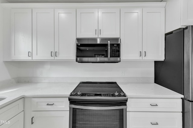 kitchen with white cabinetry, appliances with stainless steel finishes, and light stone countertops