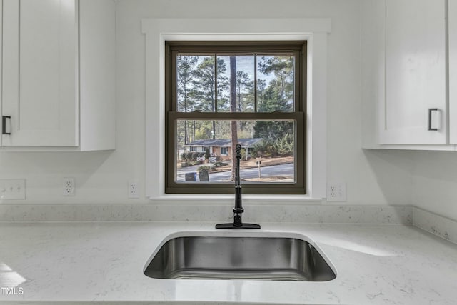 details featuring light stone countertops, sink, and white cabinets