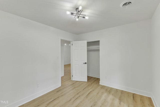 unfurnished bedroom with a closet, a chandelier, and light hardwood / wood-style flooring