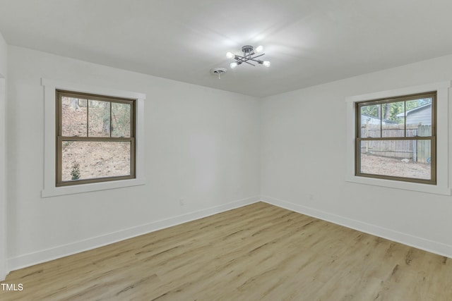 spare room with an inviting chandelier and light hardwood / wood-style floors