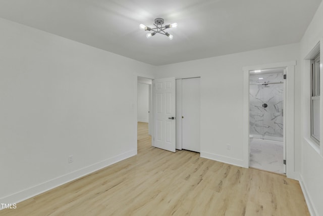 unfurnished bedroom featuring a closet, light hardwood / wood-style floors, and ensuite bath