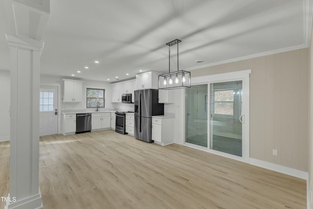 kitchen with ornate columns, hanging light fixtures, light wood-type flooring, stainless steel appliances, and white cabinets