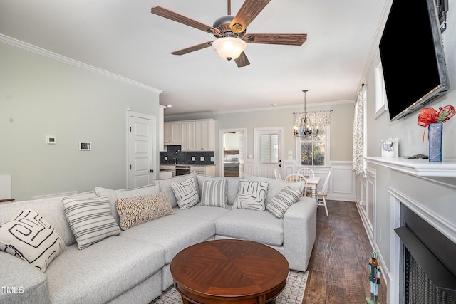 living room with ornamental molding, dark hardwood / wood-style floors, and ceiling fan with notable chandelier