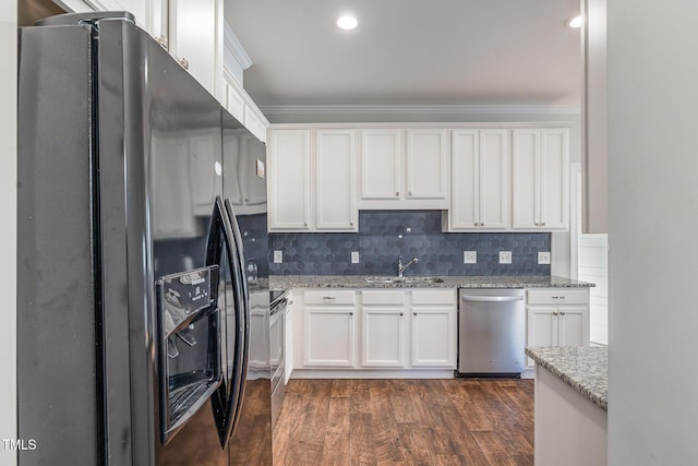 kitchen featuring appliances with stainless steel finishes, white cabinetry, backsplash, light stone countertops, and dark wood-type flooring