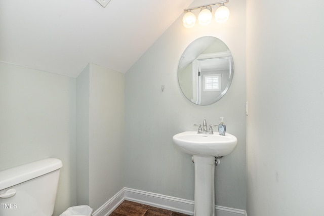 bathroom with lofted ceiling, hardwood / wood-style floors, and toilet