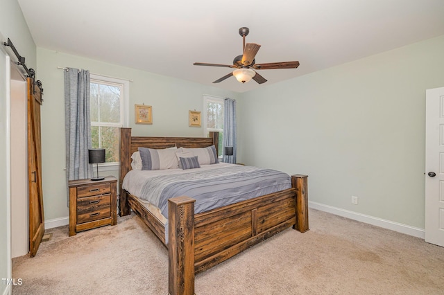 bedroom with ceiling fan, multiple windows, a barn door, and light carpet