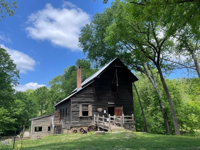 back of house featuring a wooden deck and a lawn