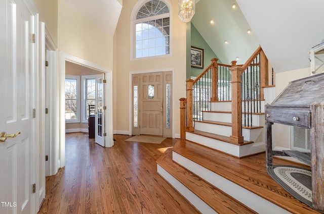 entryway with a towering ceiling, dark wood-type flooring, and a chandelier