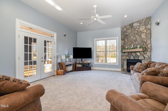 living room with a stone fireplace, light colored carpet, ceiling fan, and french doors