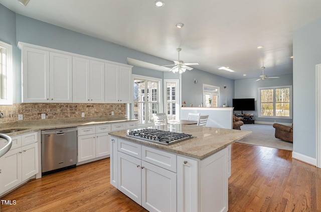 kitchen with appliances with stainless steel finishes, light stone countertops, decorative backsplash, and white cabinets