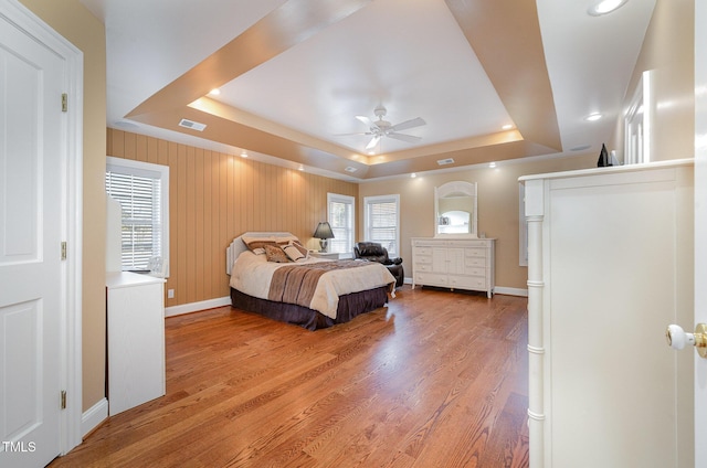 bedroom with hardwood / wood-style floors and a tray ceiling