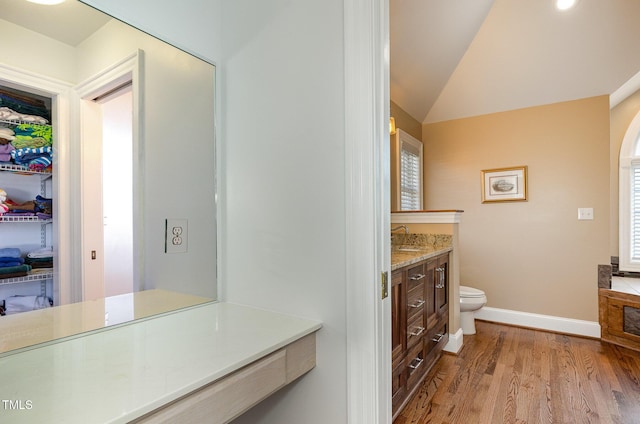 bathroom with vanity, hardwood / wood-style flooring, vaulted ceiling, and toilet