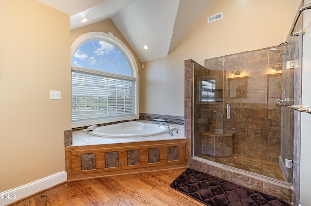 bathroom with hardwood / wood-style floors, vaulted ceiling, and separate shower and tub