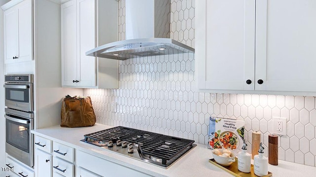 kitchen with white cabinetry, extractor fan, decorative backsplash, and stainless steel appliances