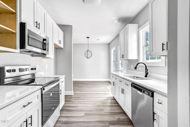 kitchen featuring pendant lighting, sink, white cabinetry, stainless steel appliances, and wood-type flooring