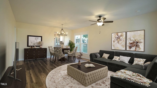 living room featuring ceiling fan with notable chandelier and dark wood-type flooring