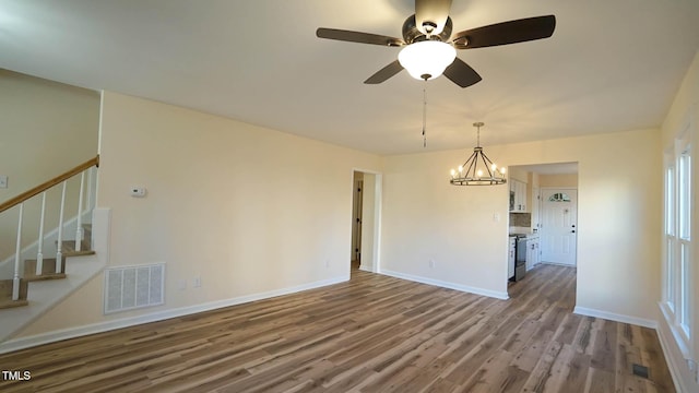 spare room featuring ceiling fan with notable chandelier and hardwood / wood-style floors