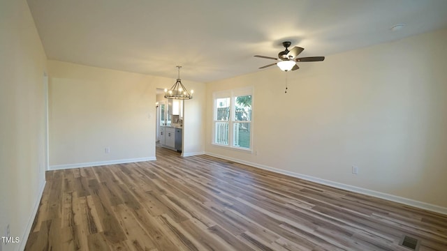 unfurnished dining area with wood-type flooring and ceiling fan with notable chandelier