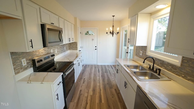 kitchen with sink, hardwood / wood-style flooring, white cabinetry, stainless steel appliances, and decorative light fixtures